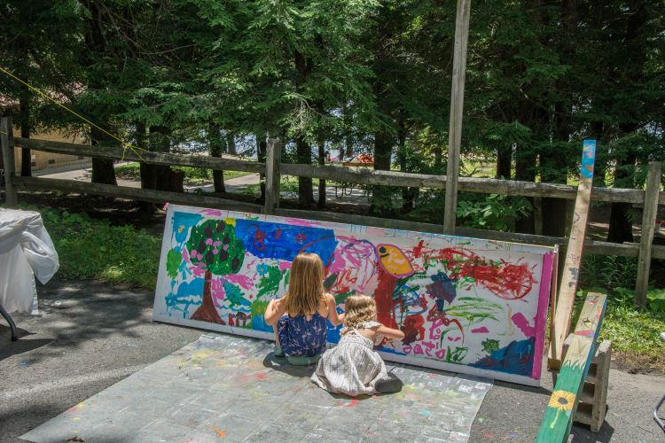 two girls painting on a long, outdoor canvas
